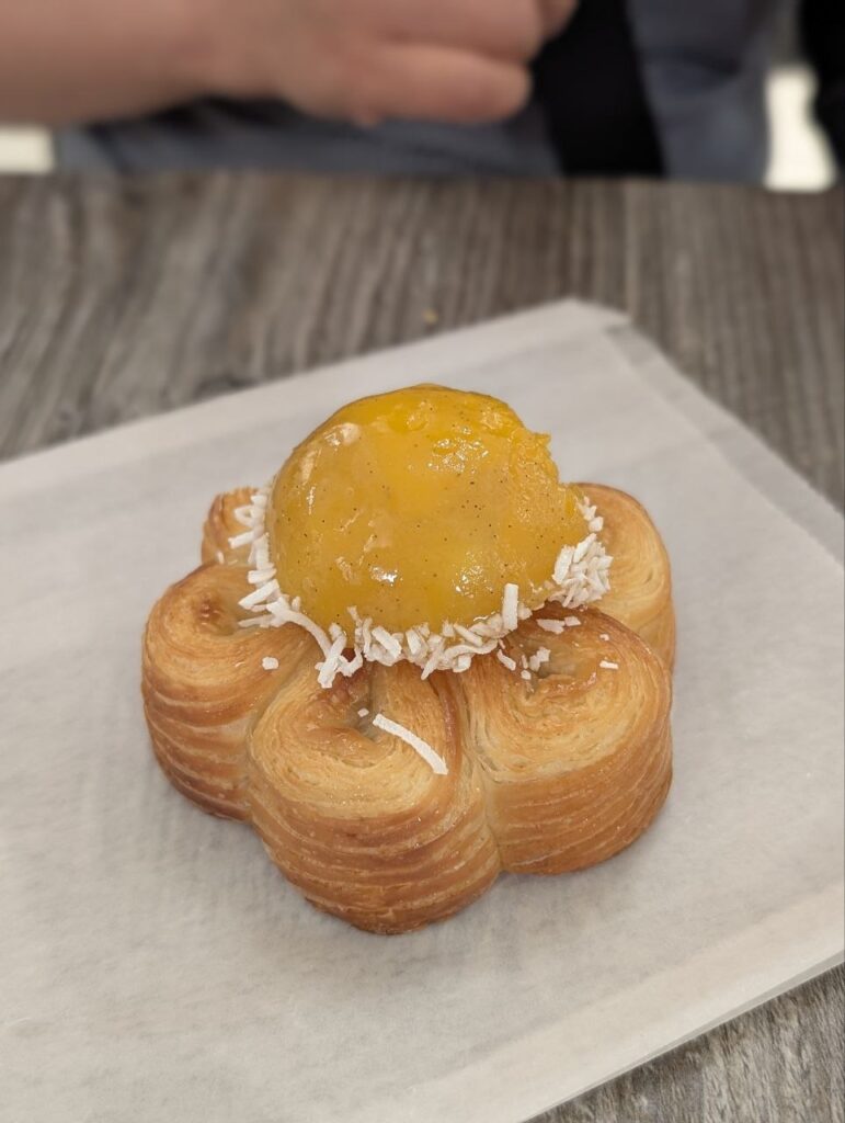 A flower-shaped Le Carousel pastry topped with a mango and pineapple dome and shredded coconut.